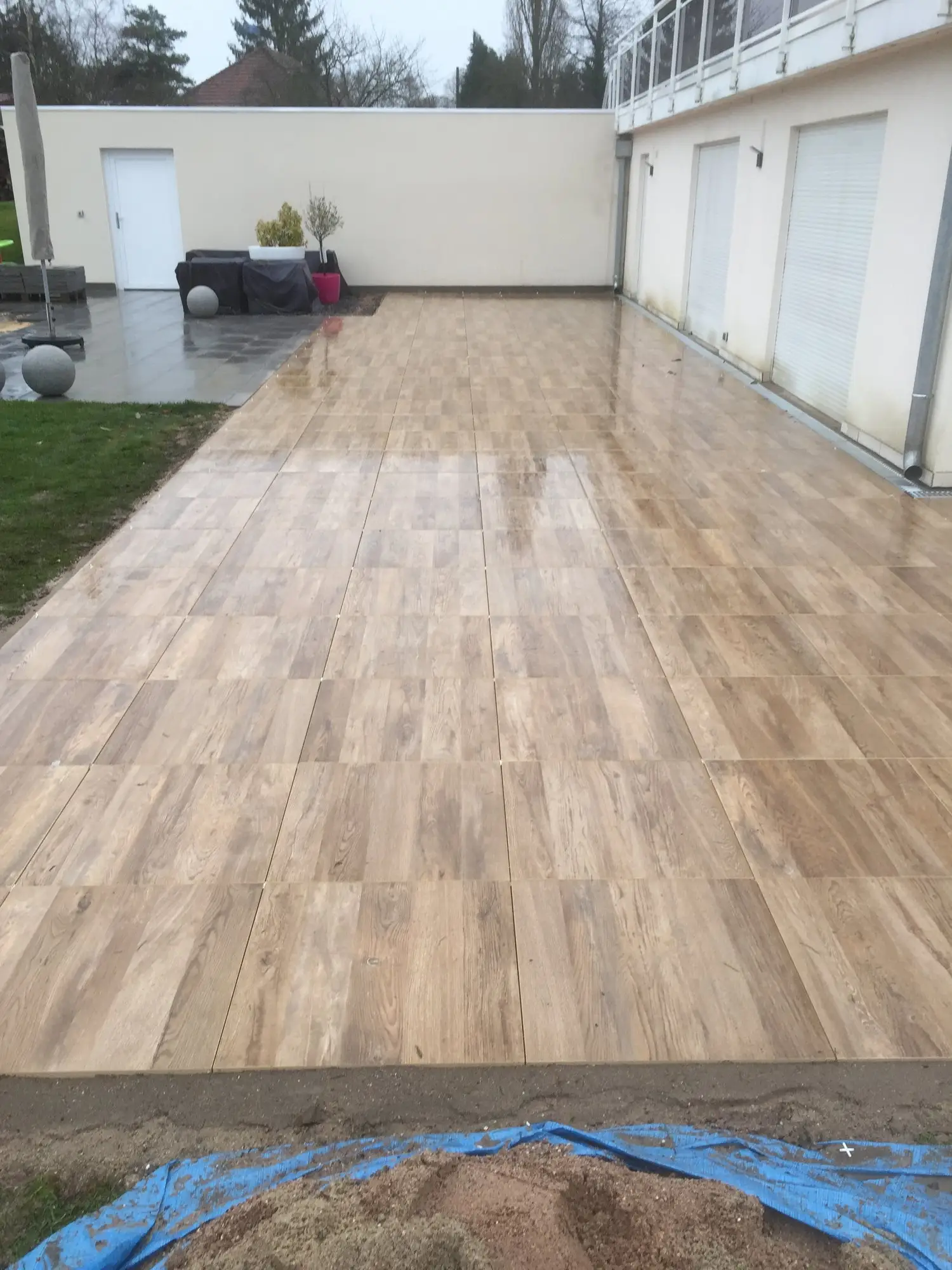 Terrasse en dalles grand format ton bois posée sous une véranda
